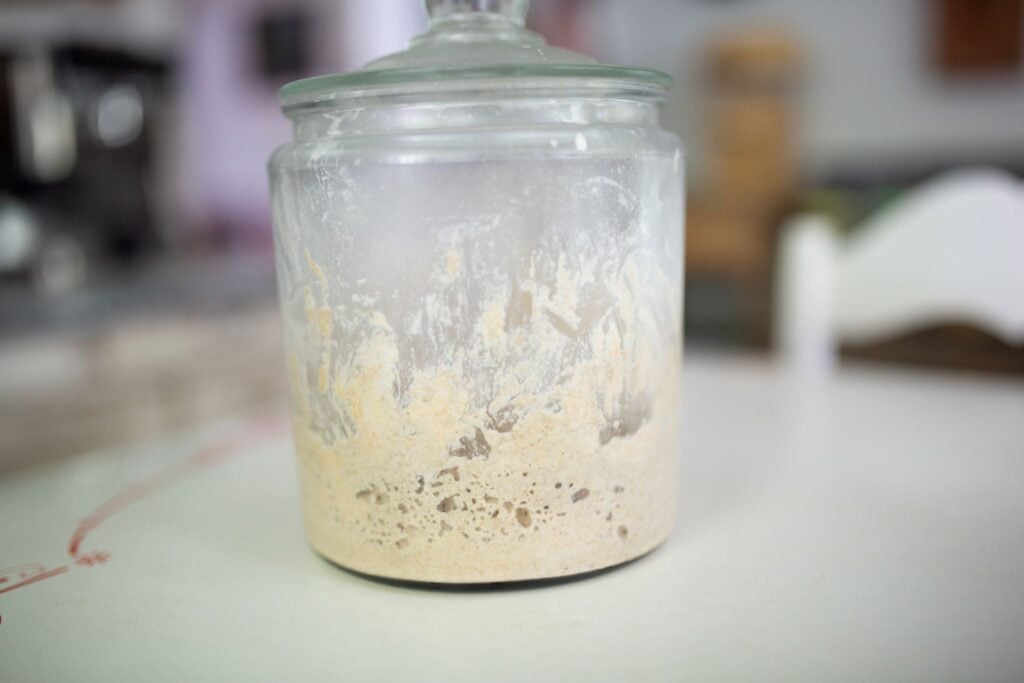 This is a jar of sourdough starter sitting on a table.