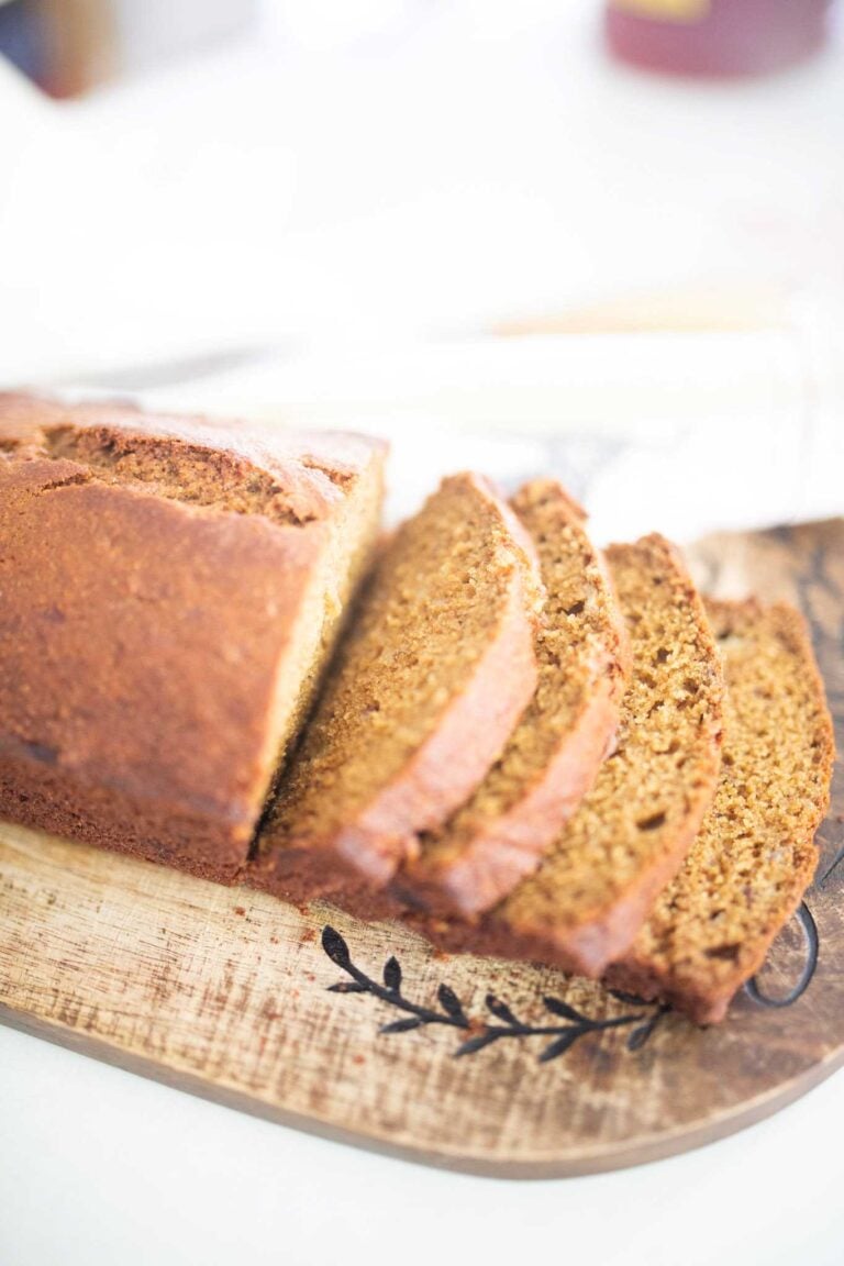 Side view of a loaf of golden brown banana bread that is halfway sliced through.