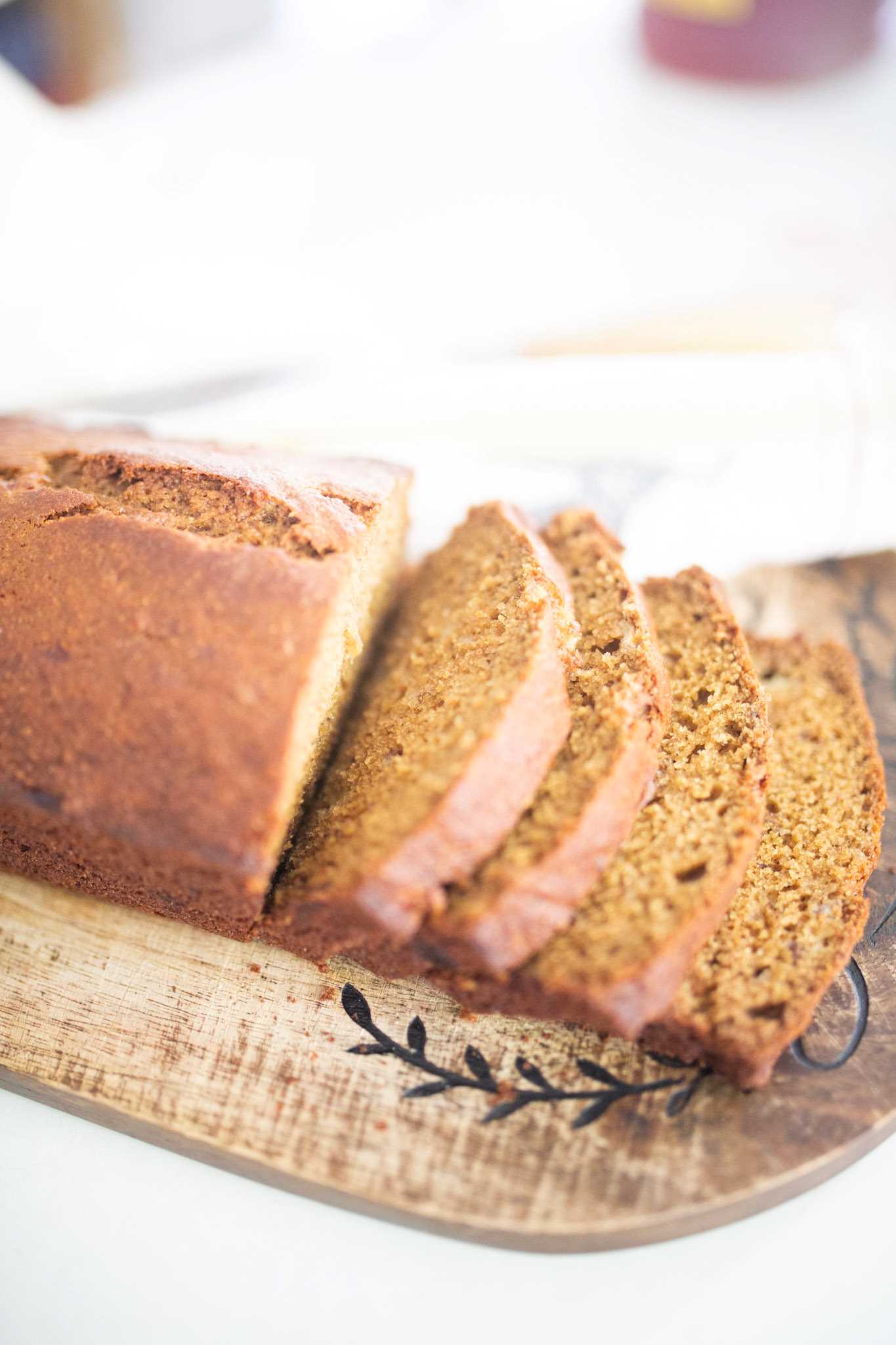 Side view of a loaf of golden brown banana bread that is halfway sliced through.