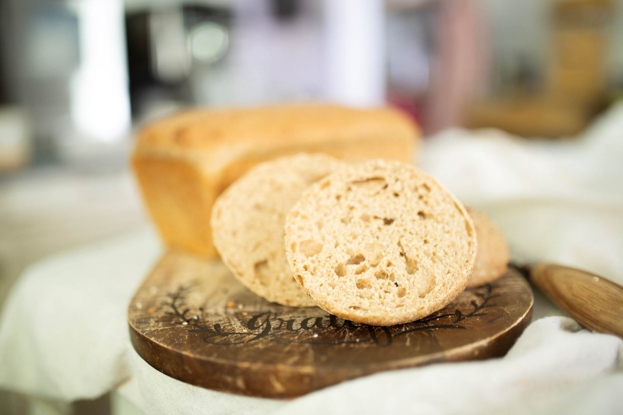 A sourdough hamburger bun and loaf of sandwich bread from the master sourdough dough recipe on a cutting board