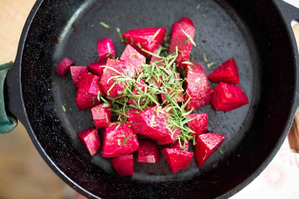 Chopped beets, olive oil, salt, and rosemary in a cast iron skillet.