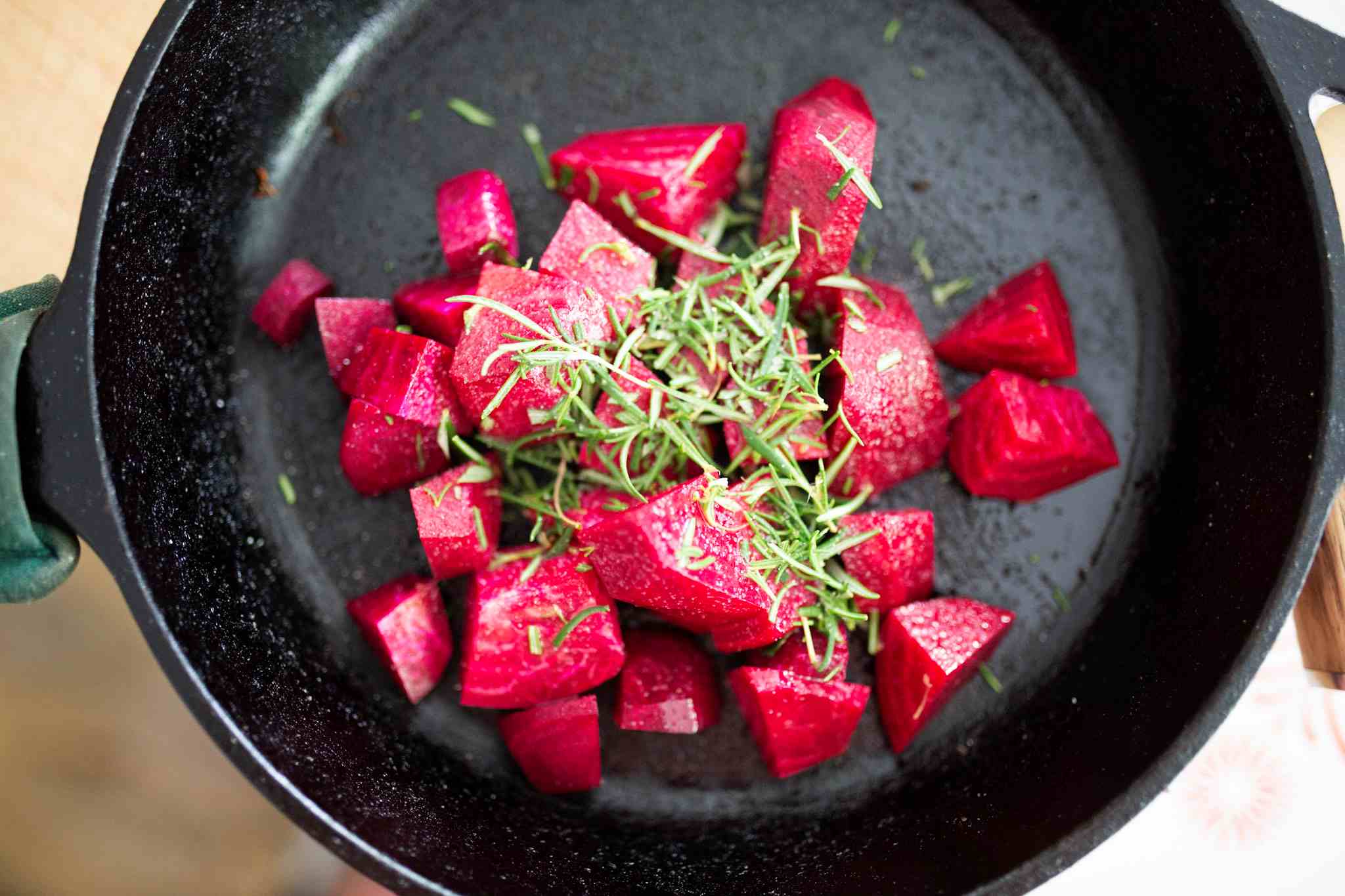 Chopped beets, olive oil, salt, and rosemary in a cast iron skillet.