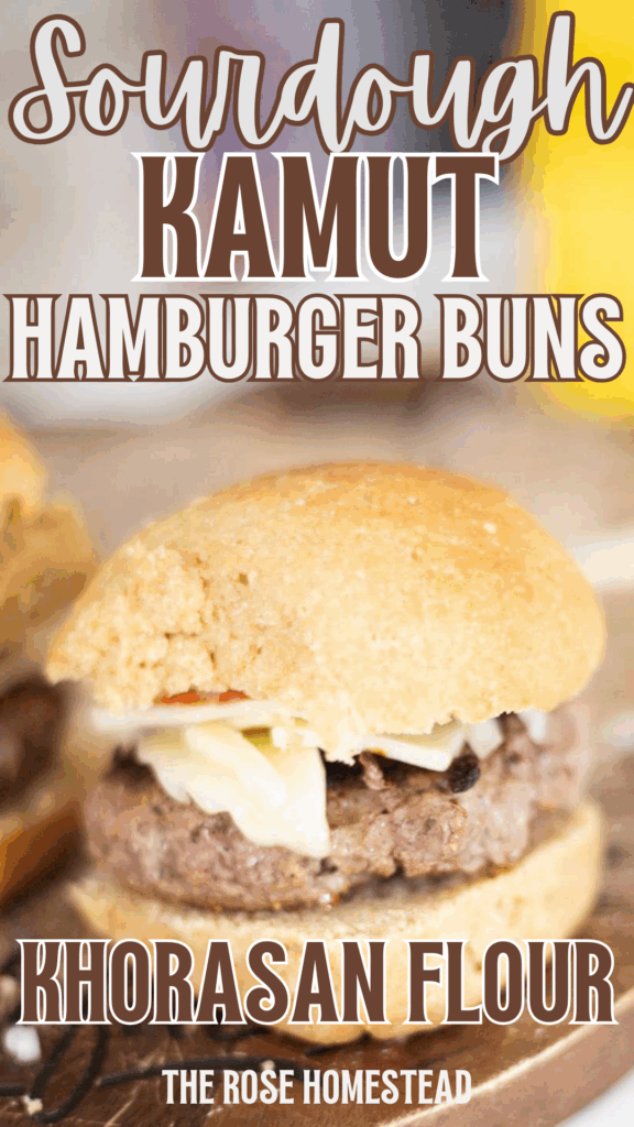 This is a pinterest pin for sourdough Kamut hamburger buns with a photo of a hamburger sitting on a cutting board. The soft sourdough kamut bun is golden brown and the text reads sourdough kamut hamburger buns, khorasan flour.