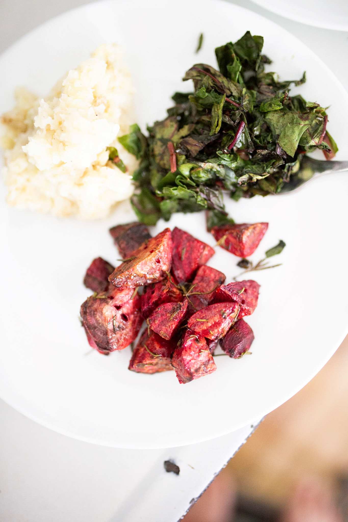 Roasted rosemary beets on a plate with mashed potatoes and greens.