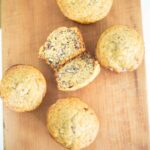 This is an overhead photo of 5 fresh milled banana nut muffins with the middle muffin cut open to show its soft crumb.