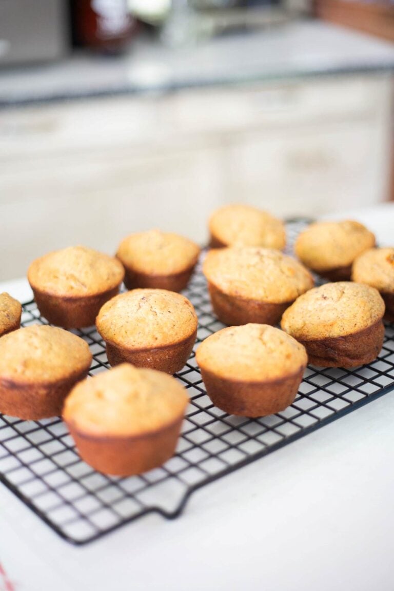 Fresh milled banana nut muffins are on a wire rack to cool after baking.