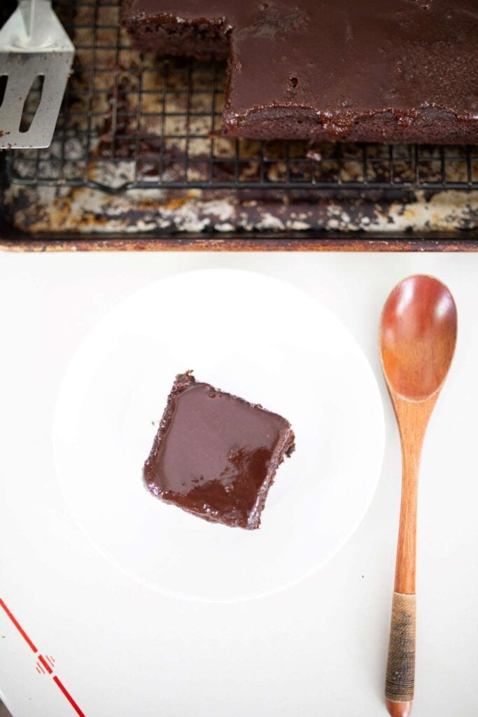 there is a piece of fresh milled chocolate cake on a white plate with a wooden spoon to the side