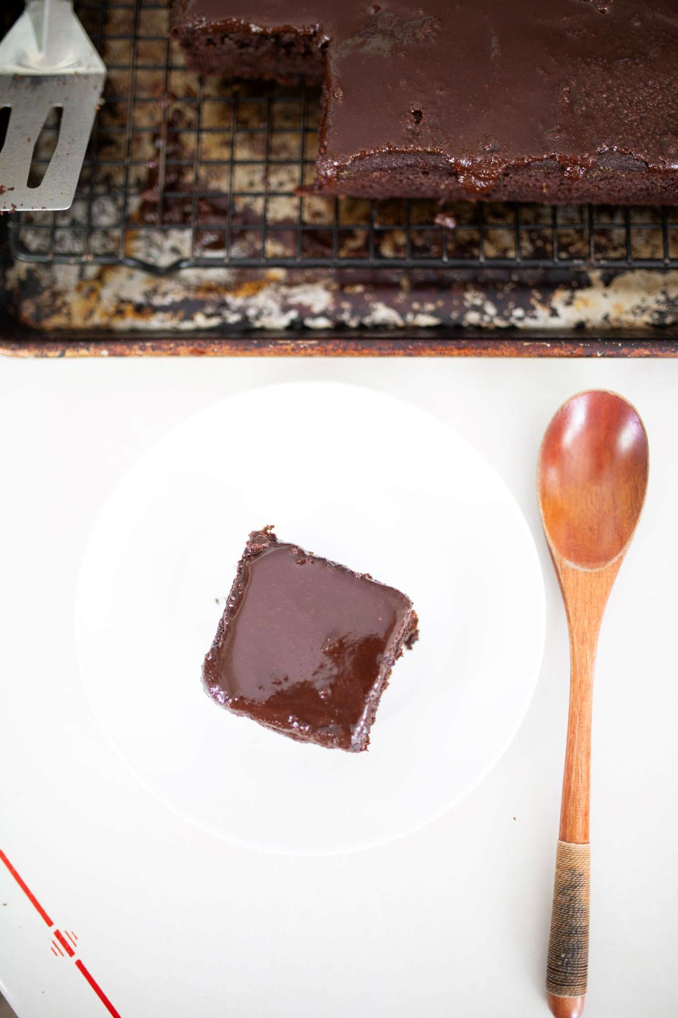 there is a piece of fresh milled chocolate cake on a white plate with a wooden spoon to the side
