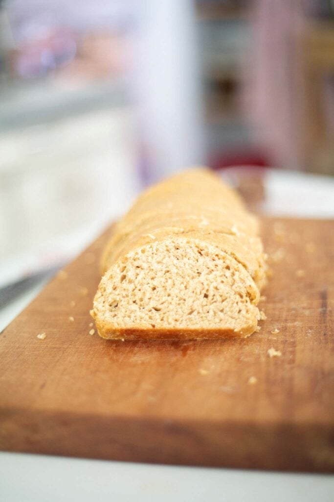 Looking onto a slice of sourdough french bread made from fresh milled flour sitting on a wooden cutting board.