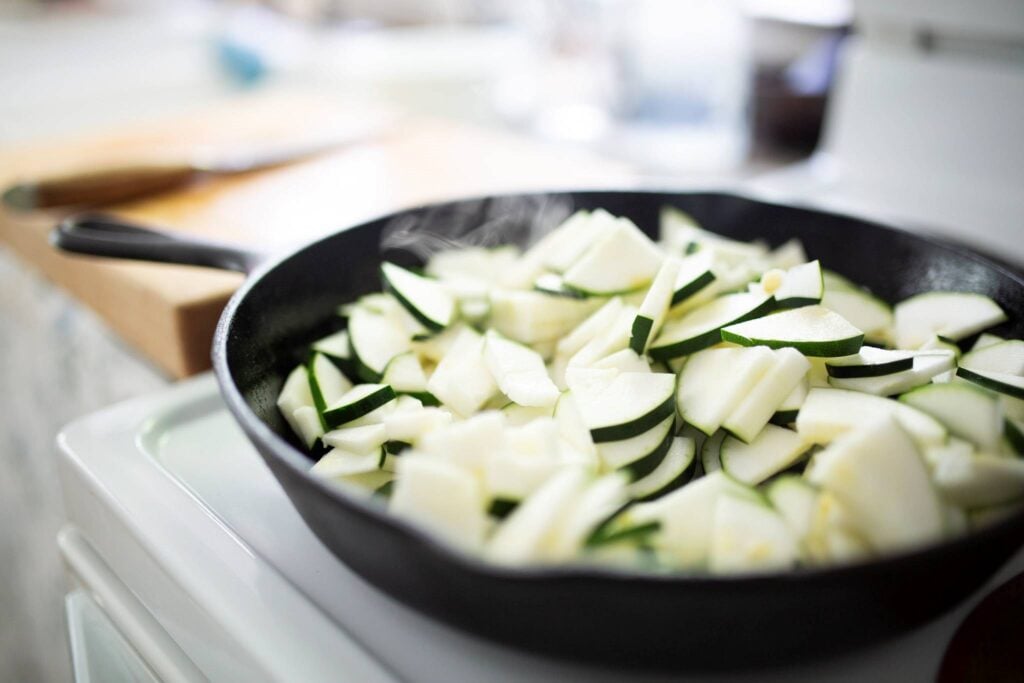 Sliced zucchini and onion in a cast iron skillet.