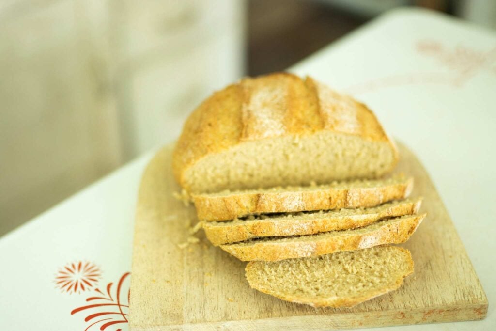 Fresh milled flour artisan bread on a cutting board. The loaf has a few slices laying in front.