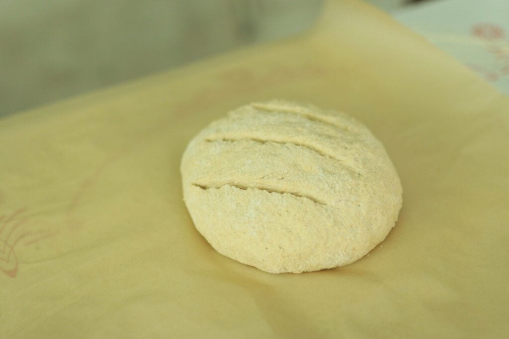 This is the fresh milled artisan bread dough scored and on a piece of parchment paper.