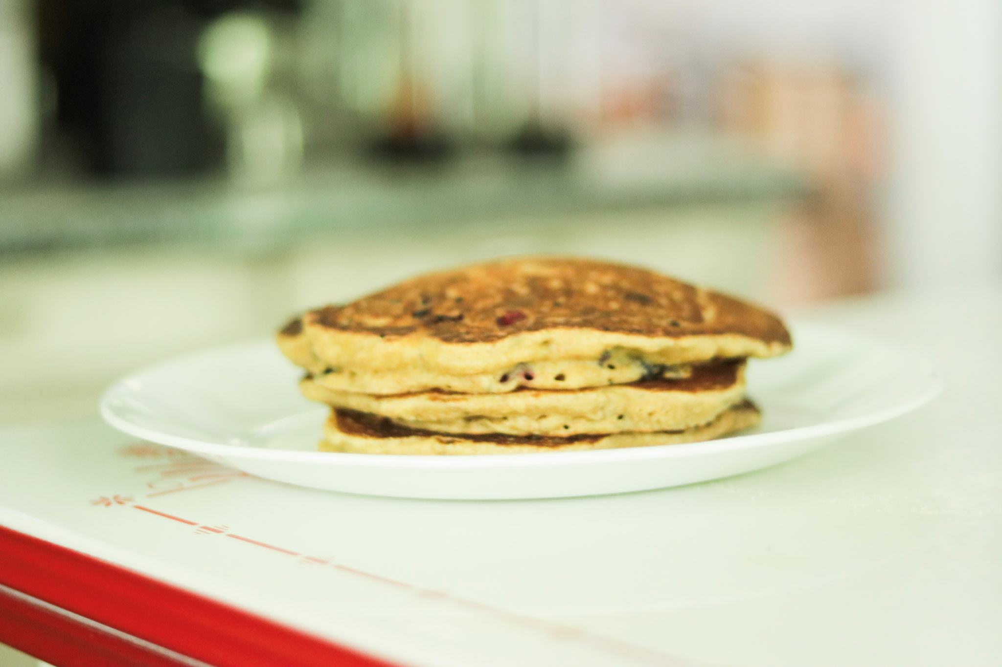 A plate is stacked with Einkorn flour pancakes sitting on a table.