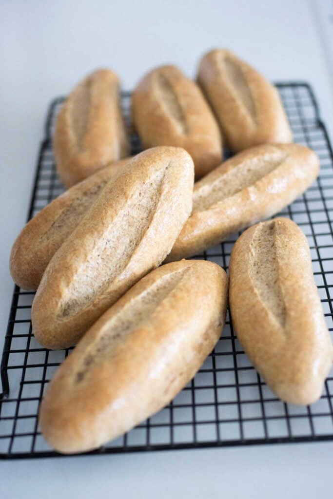 Fresh milled hoagie rolls stacked on a wire rack