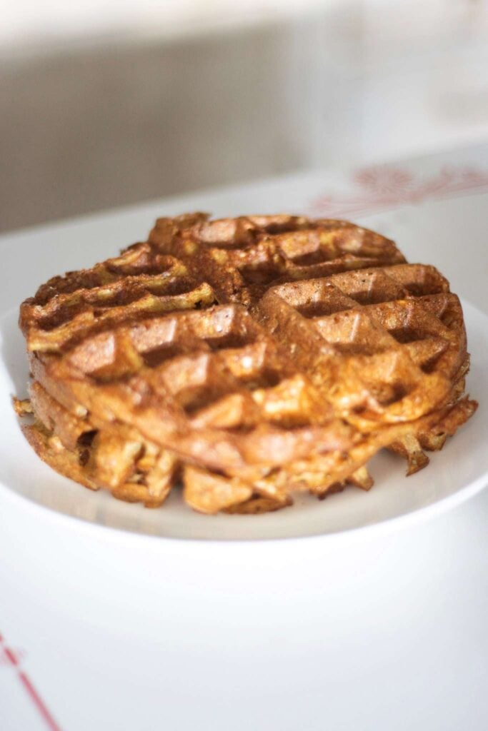 This is a close up of a stack of sourdough discard waffles on a plate on a white table top