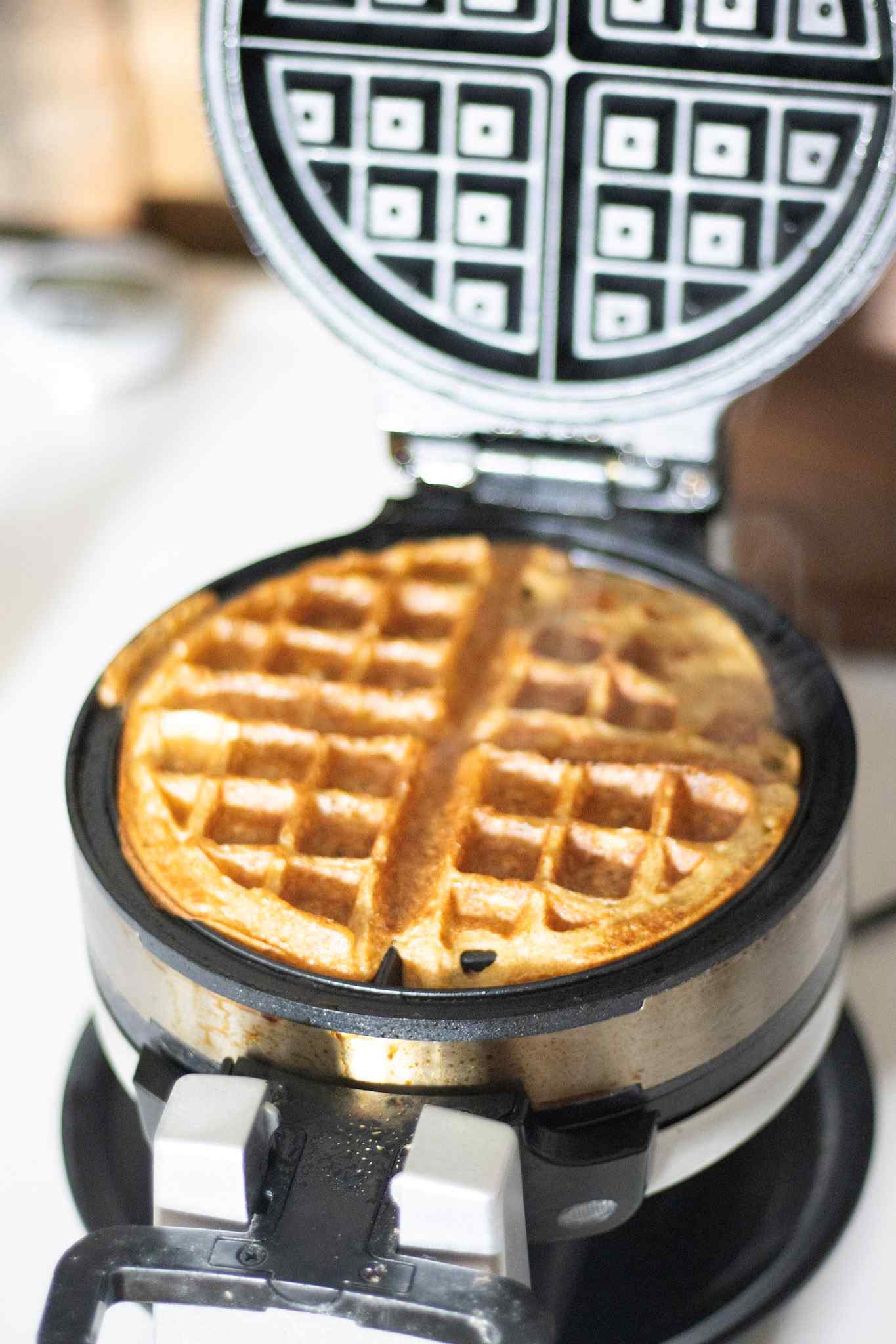 A sourdough discard waffle cooked to golden brown still in the waffle maker