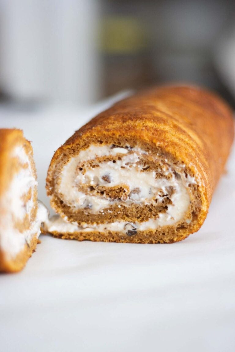 fresh milled pumpkin roll is sliced in half to show the cream cheese swirl