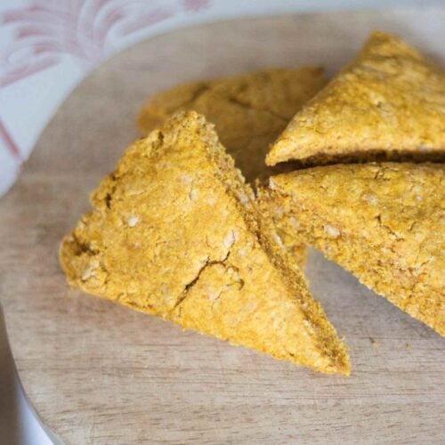 overhead photo of fresh milled pumpkin scones sitting on a wooden cutting board.