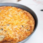 fresh milled pizza just out of the oven in a gray pizza pan. The top is golden brown.