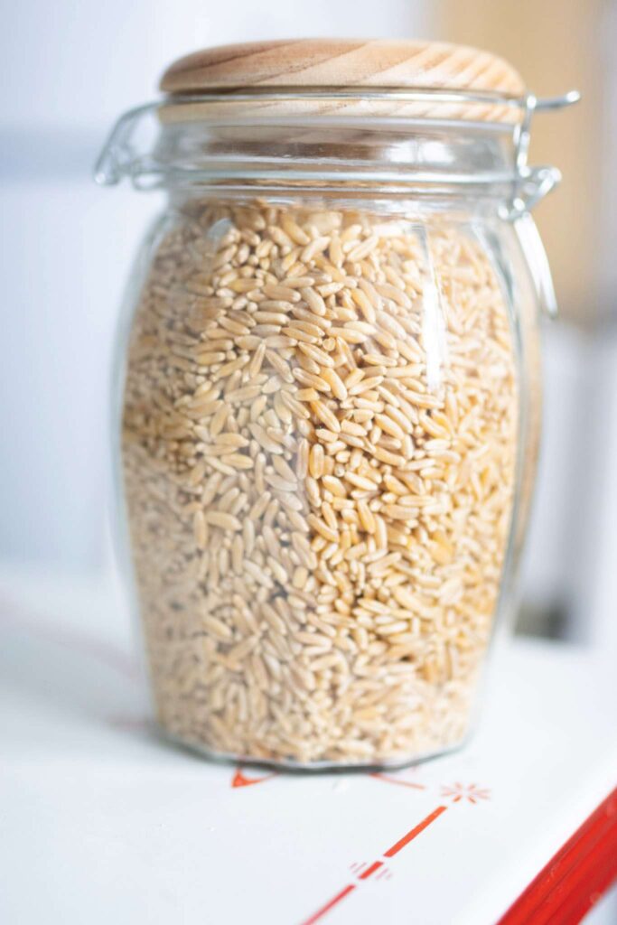 A beautiful glass jar with a wooden lid full of Kamut wheat berries. This is used for short term storage.