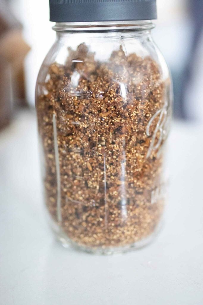 A mason jar full of oat free granola with a gray lid sitting on a white counter top.