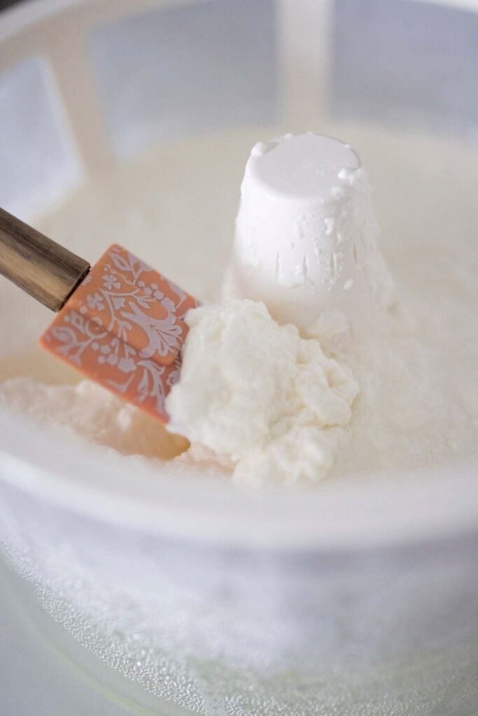 A spatula has yogurt on it. The yogurt is in a yogurt strainer.