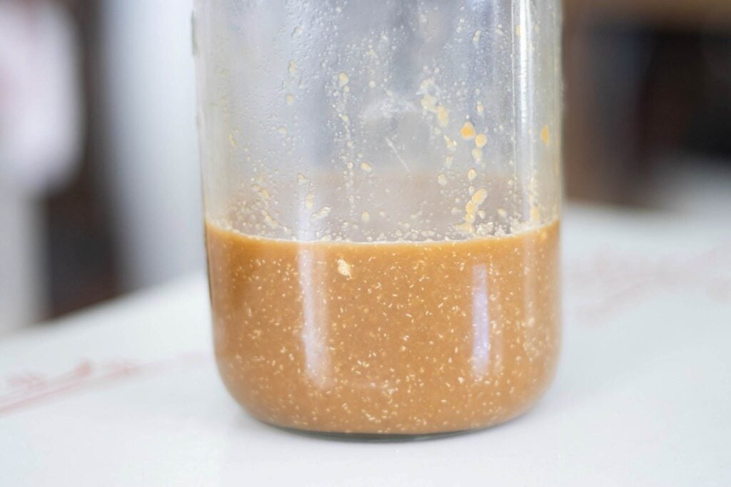 Jar of potato flake starter. The liquid is brown in color.