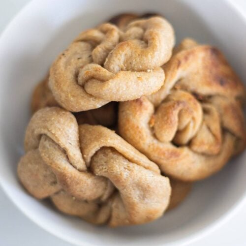 Overhead photo of a white bowl with garlic knots piled in it.