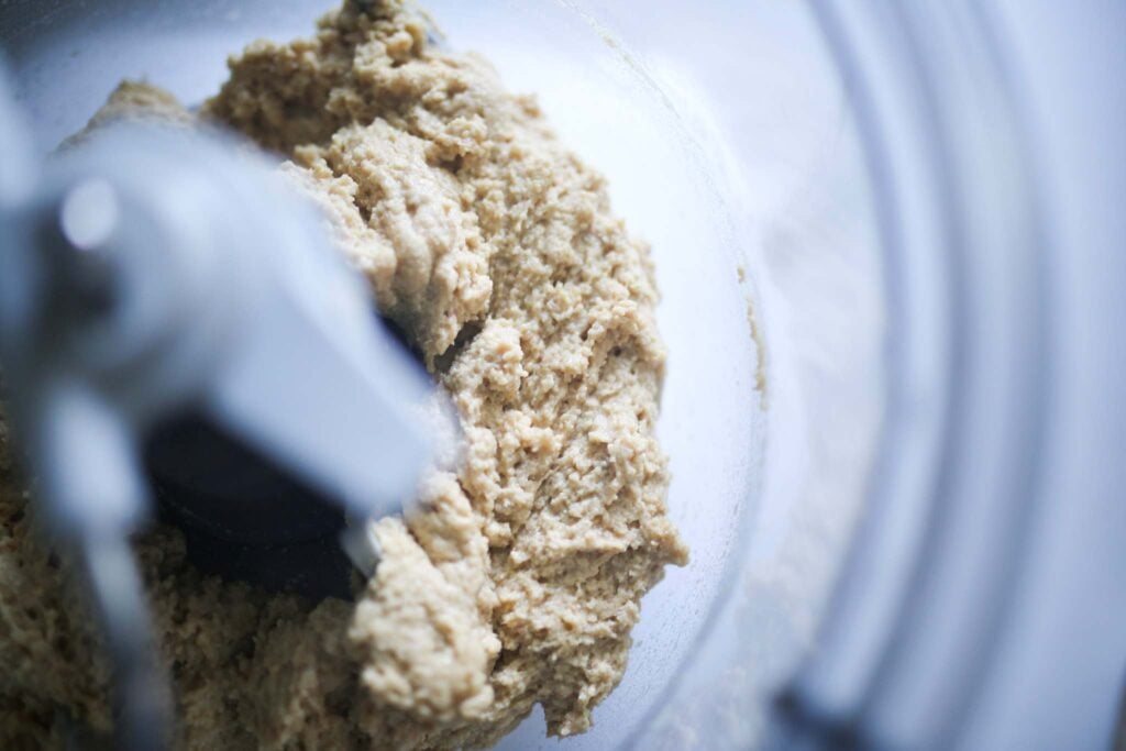 There is shaggy dough in a clear stand mixer bowl.