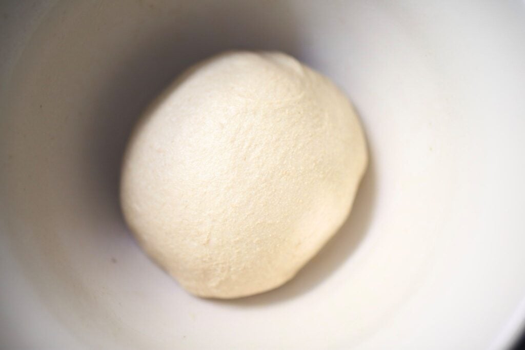 There is a ball of dough in a white bowl.