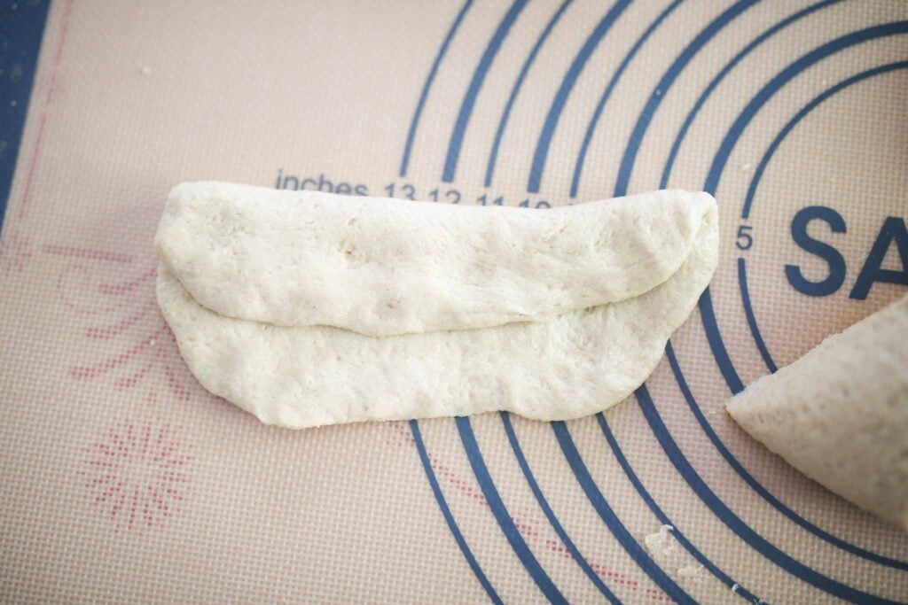 Hoagie sandwich dough is pressed out with on side folded over into itself during shaping.