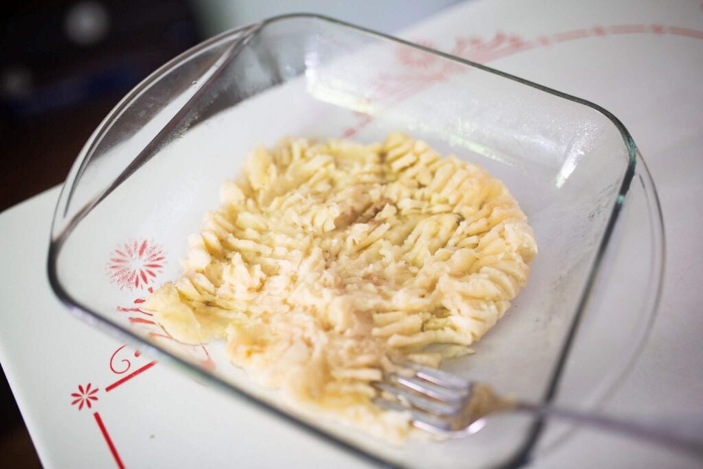 Mashed bananas in a glass square pan.