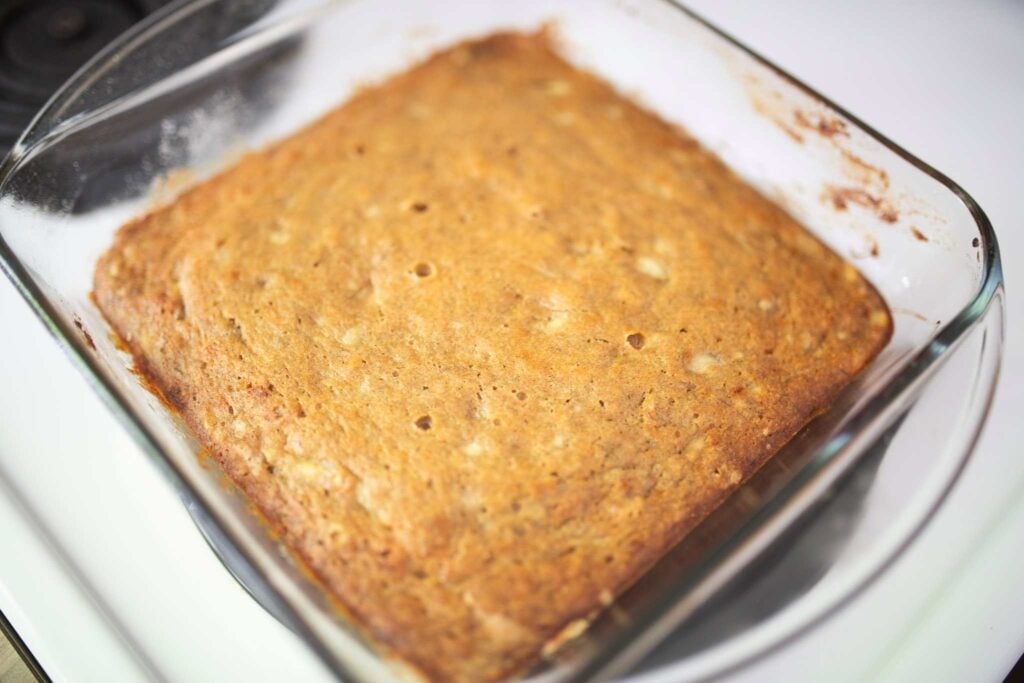 Glass pan of banana bars just out of the oven that have not been sliced yet.