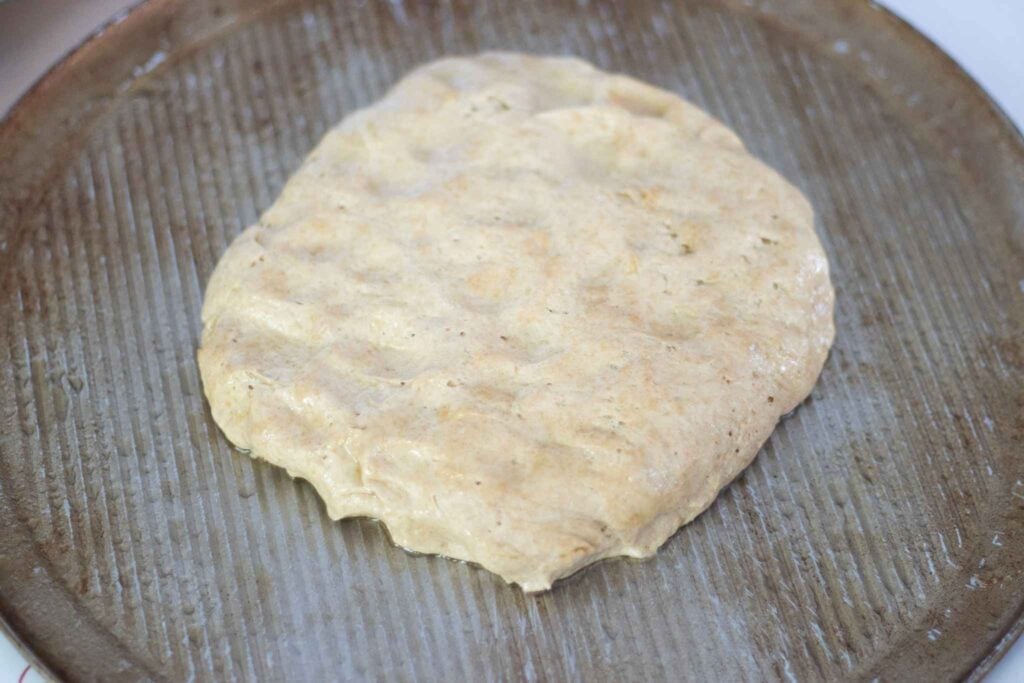 Pizza dough ball sitting on a silver pizza pan.