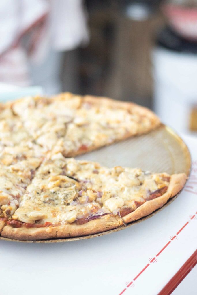 Pizza on a pizza pan with one slice missing.