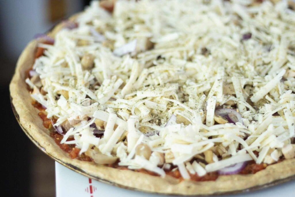 Pizza dough is topped with toppings and shredded cheese.