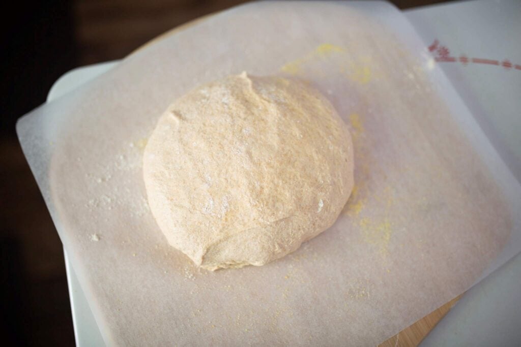 A ball of dough sits on a piece of parchment paper.