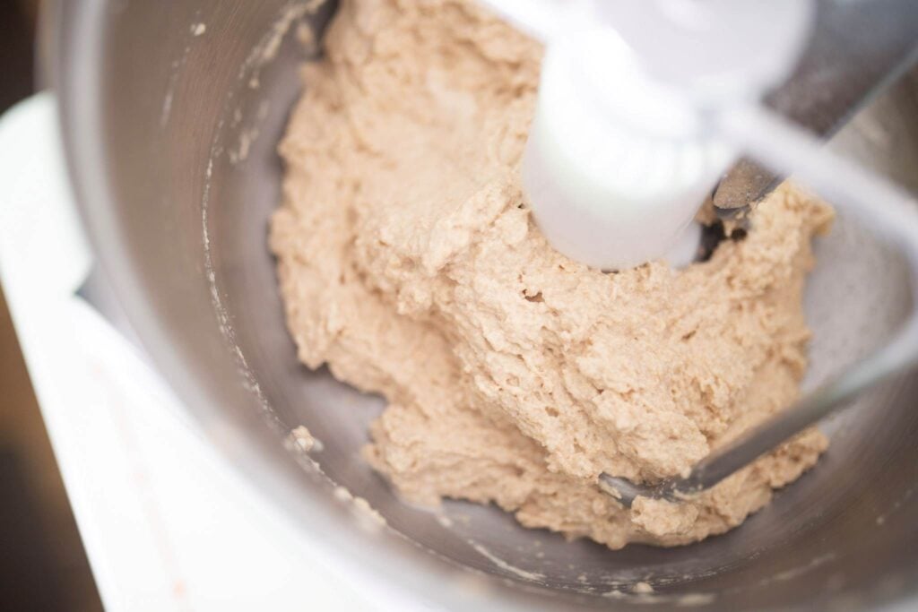 There is shaggy dough in a stainless steel mixer bowl.