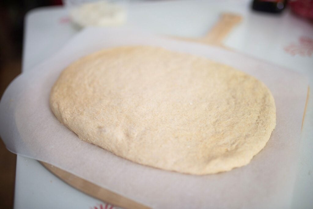 dough is rolled out into a rectangle on a piece of parchment paper.