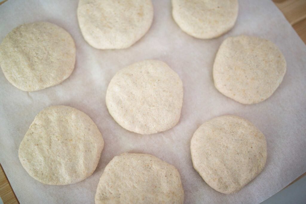 An overhead shot of shaped hamburger bun dough.