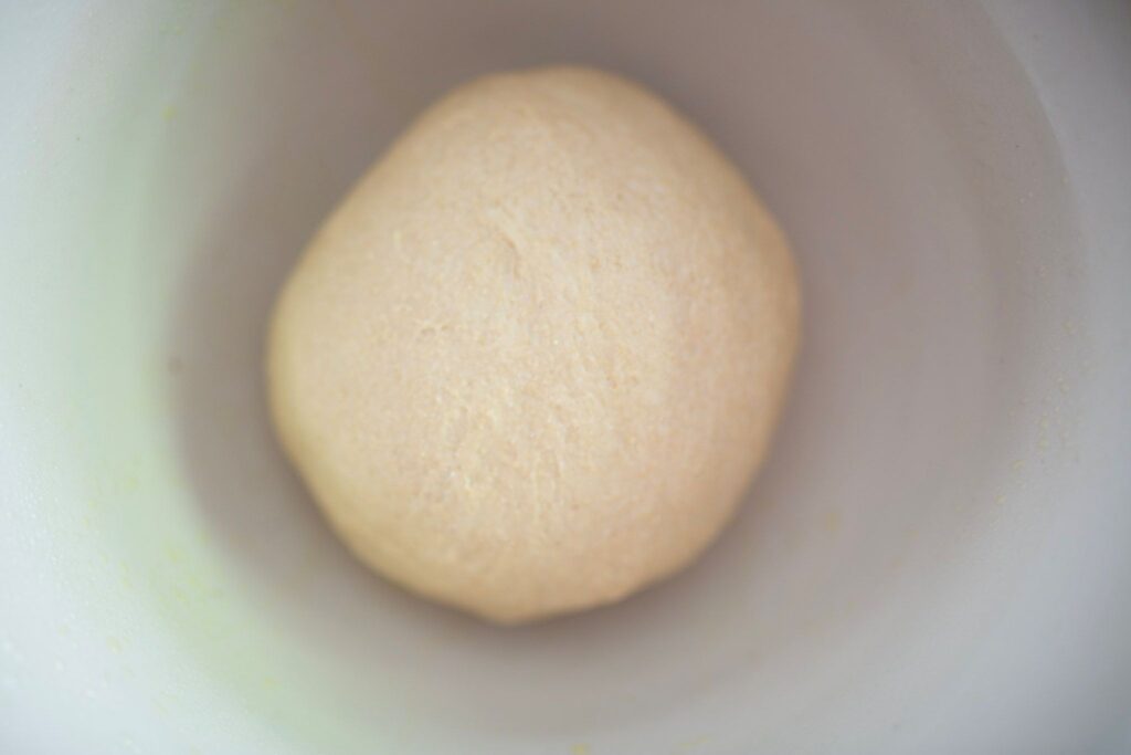 Dough ball in a cream colored bowl.