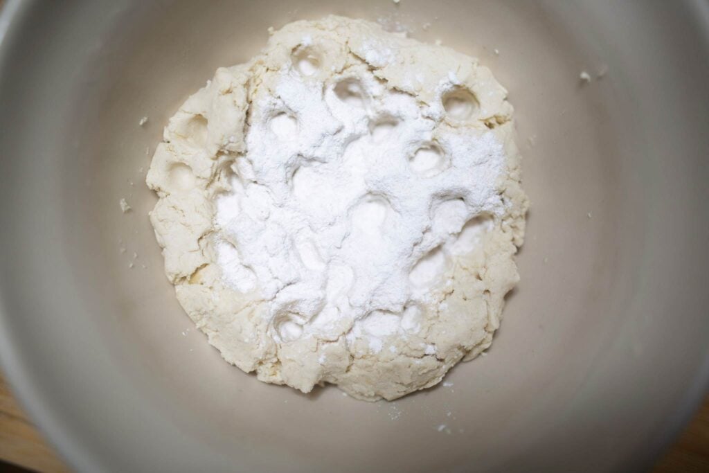 Biscuit dough that has been dimpled and sprinkled with a salt mixture in a white mixing bowl.