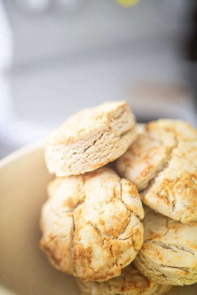 A stack of golden brown biscuits in a cream colored bowl.