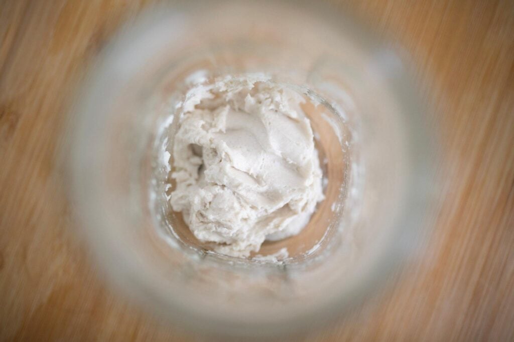 There is some dough in the bottom of a mason jar shown from overhead.