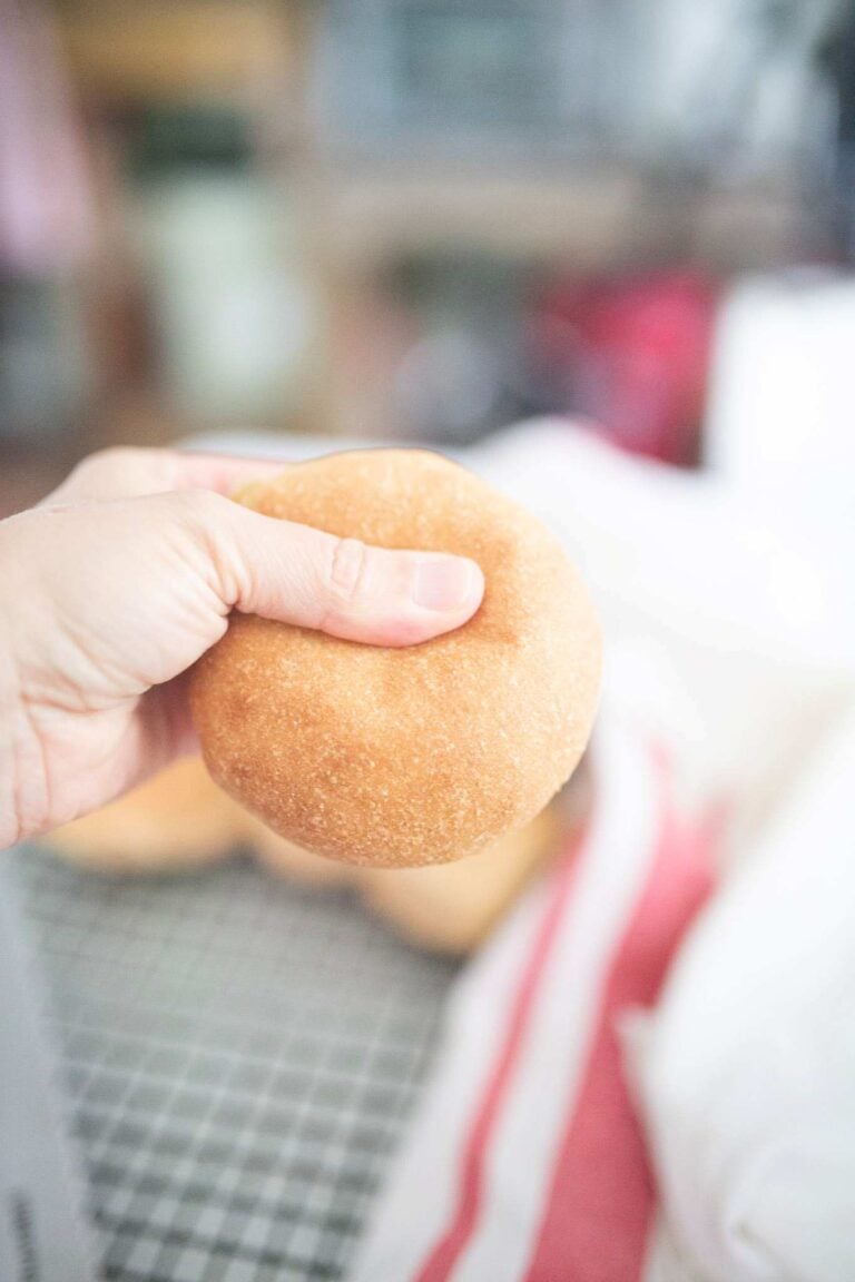 Hand holding a hamburger bun and squeezing it.