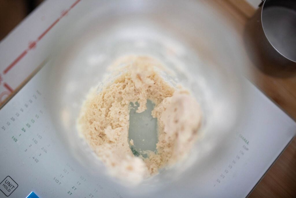 Looking down into a jar of sourdough starter that has been scooped out leaving on a little bit in the jar.