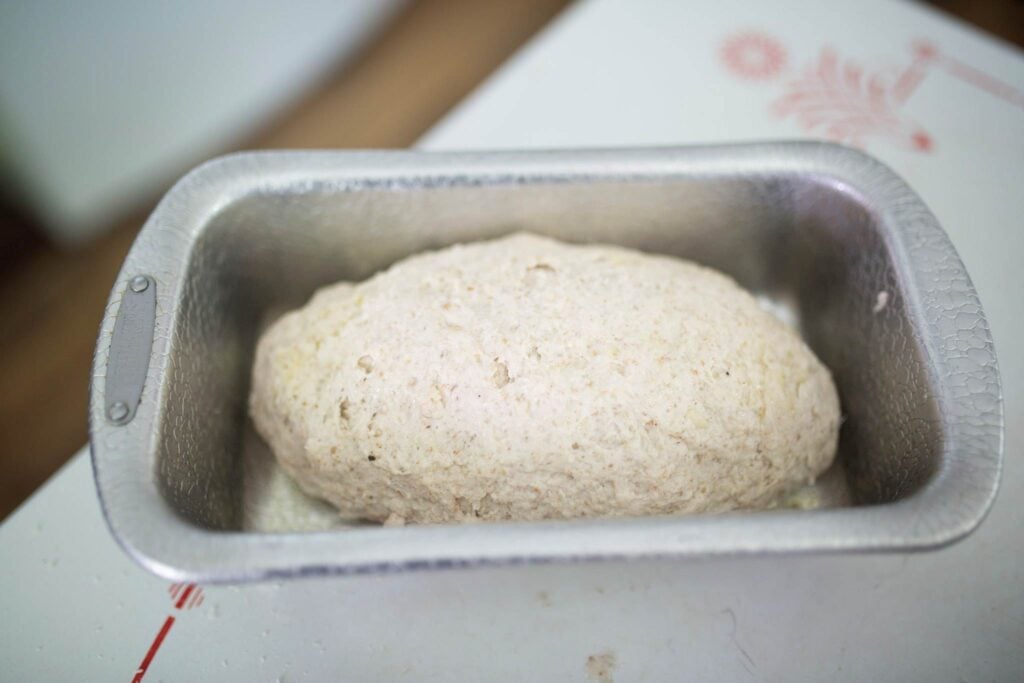 Bread dough shaped and in a metal loaf pan.