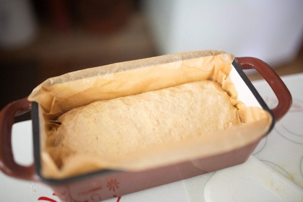 Bread dough in a red bread pan.