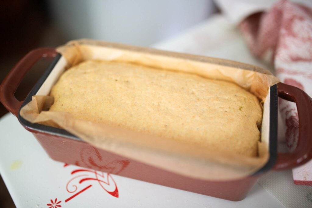 Bread dough risen in red bread pan.