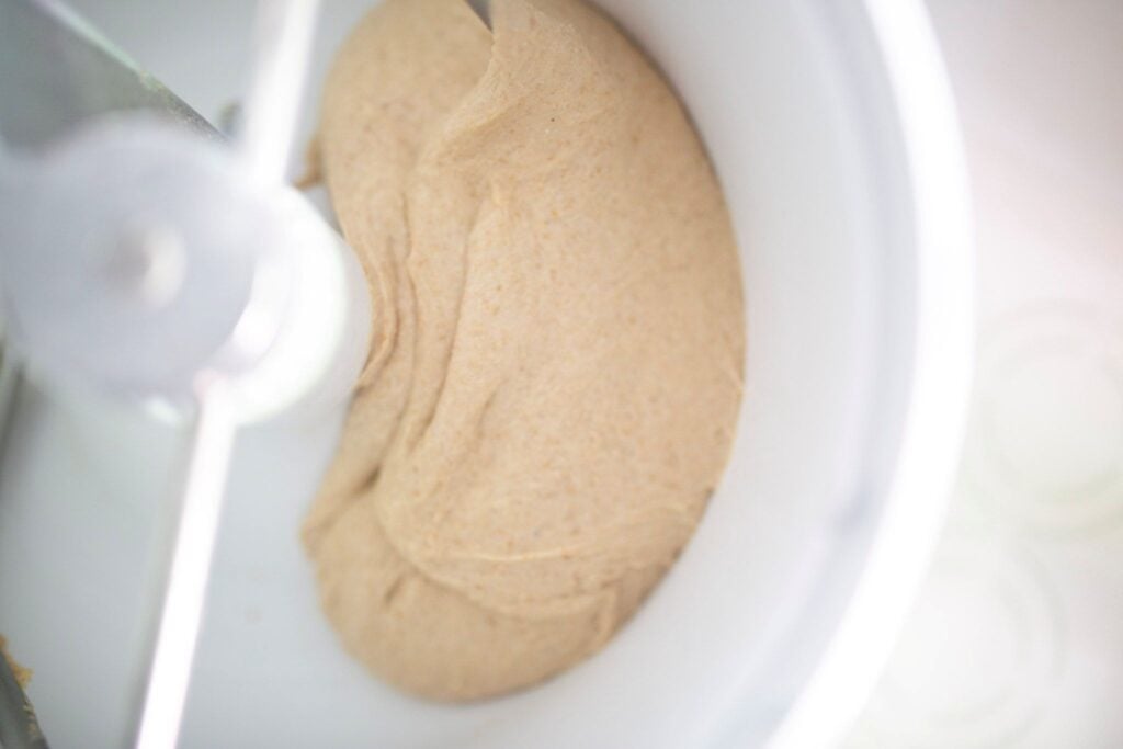 Bread dough in the stand mixer is kneaded and is smooth and glossy.